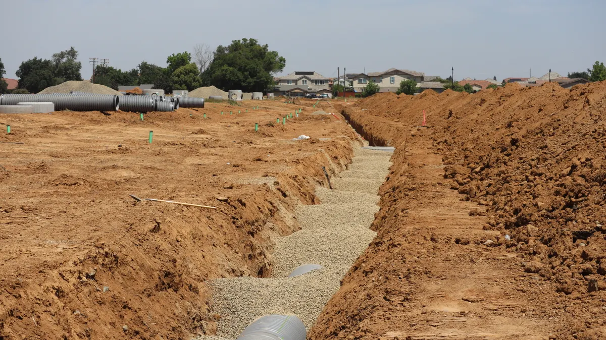 Trenchless Sewer Line Repair Oakland CA — construction site with trenches and large pipes in a suburban setting